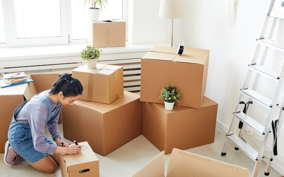 Woman writing on moving boxes.